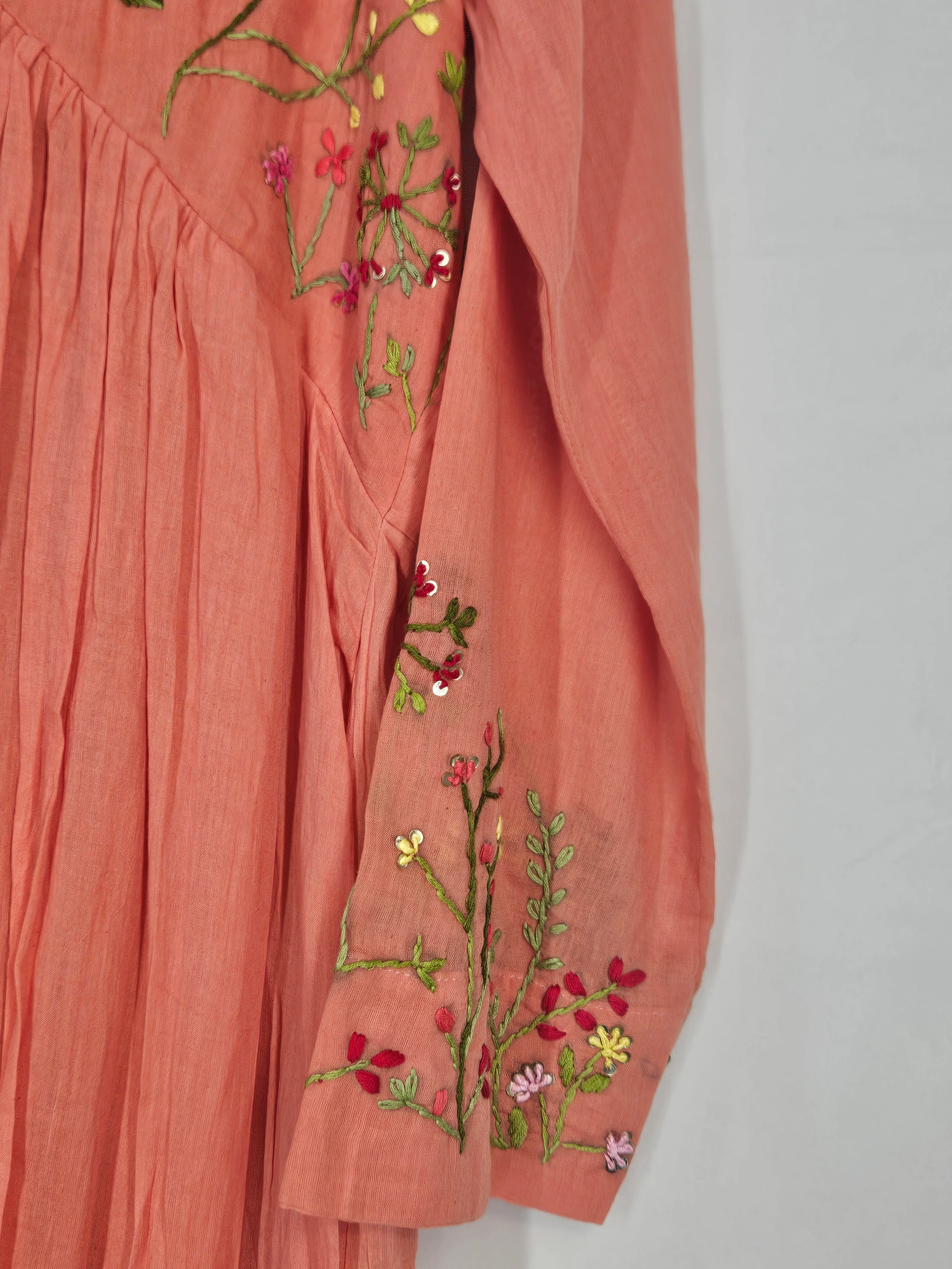 Pure mul cotton 2-piece ethnic set in peach with intricate floral embroidery on the sleeve and pleated detailing.