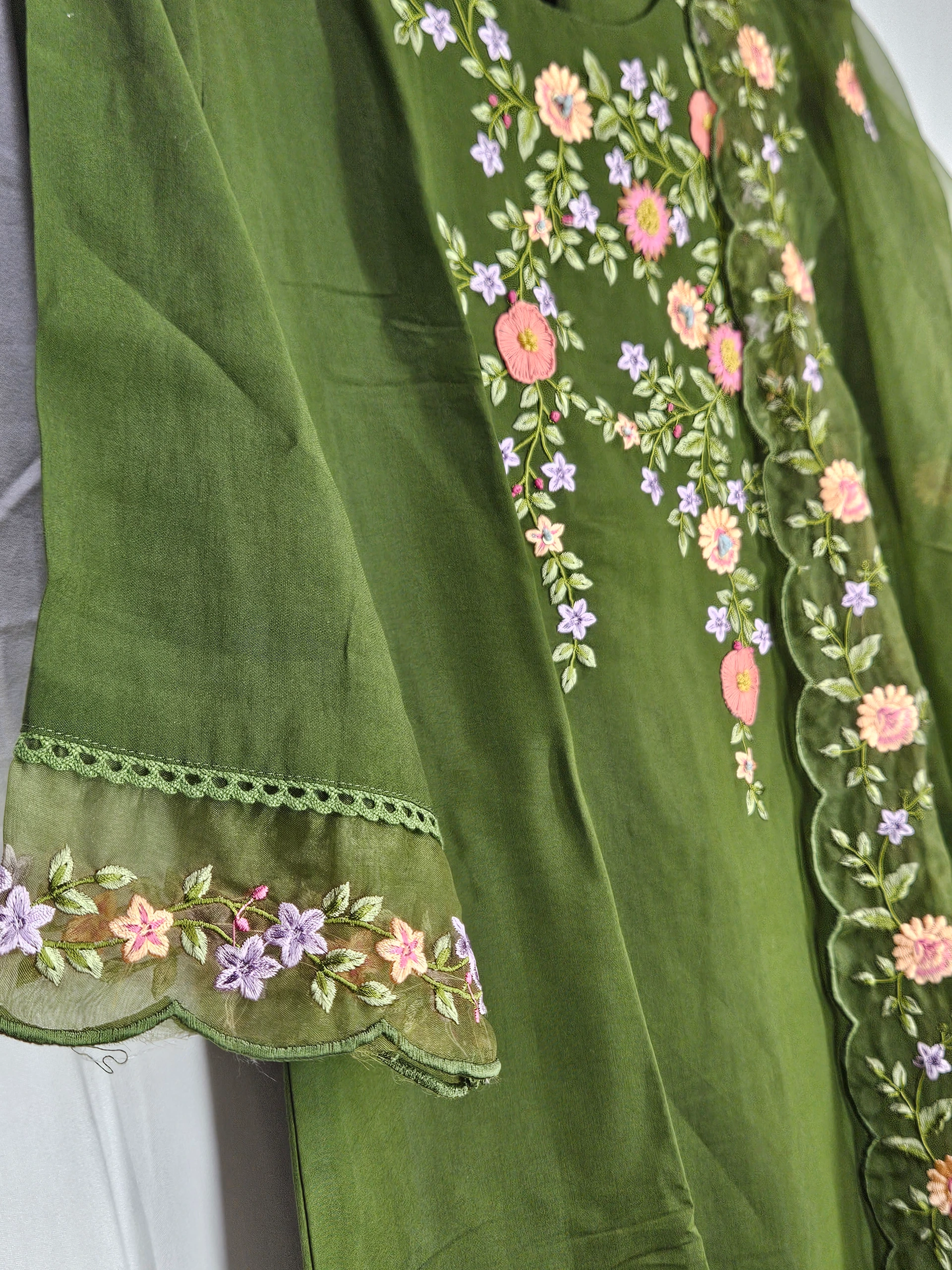 Green pure muslin ethnic lehenga dress with intricate floral embroidery in pink and purple, perfect for weddings and festivals.
