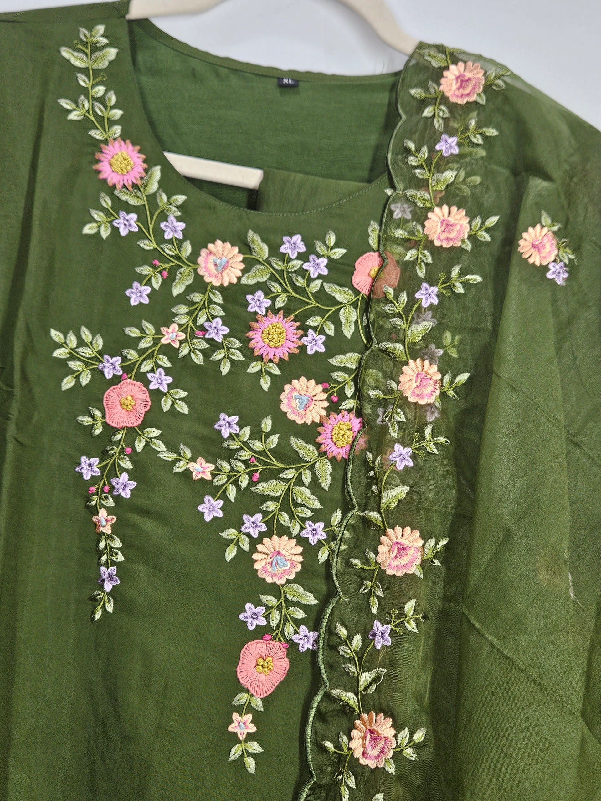 Green pure muslin ethnic lehenga dress with intricate floral embroidery in pink, yellow, and lavender hues, perfect for weddings and festivals.