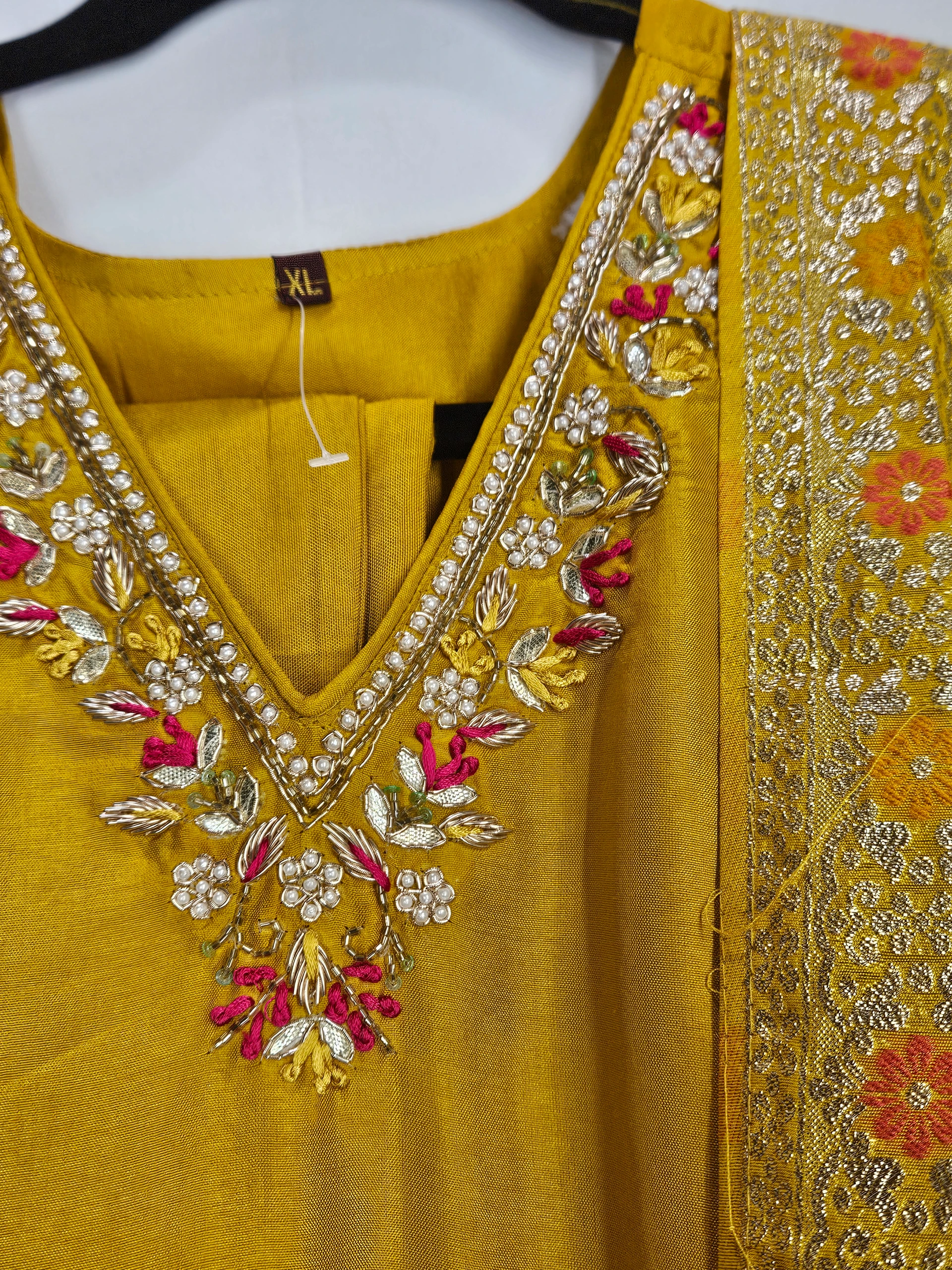 Exquisite mustard yellow pure Dola silk dress with intricate floral embroidery in pink, gold, and green, perfect for weddings and festive celebrations.