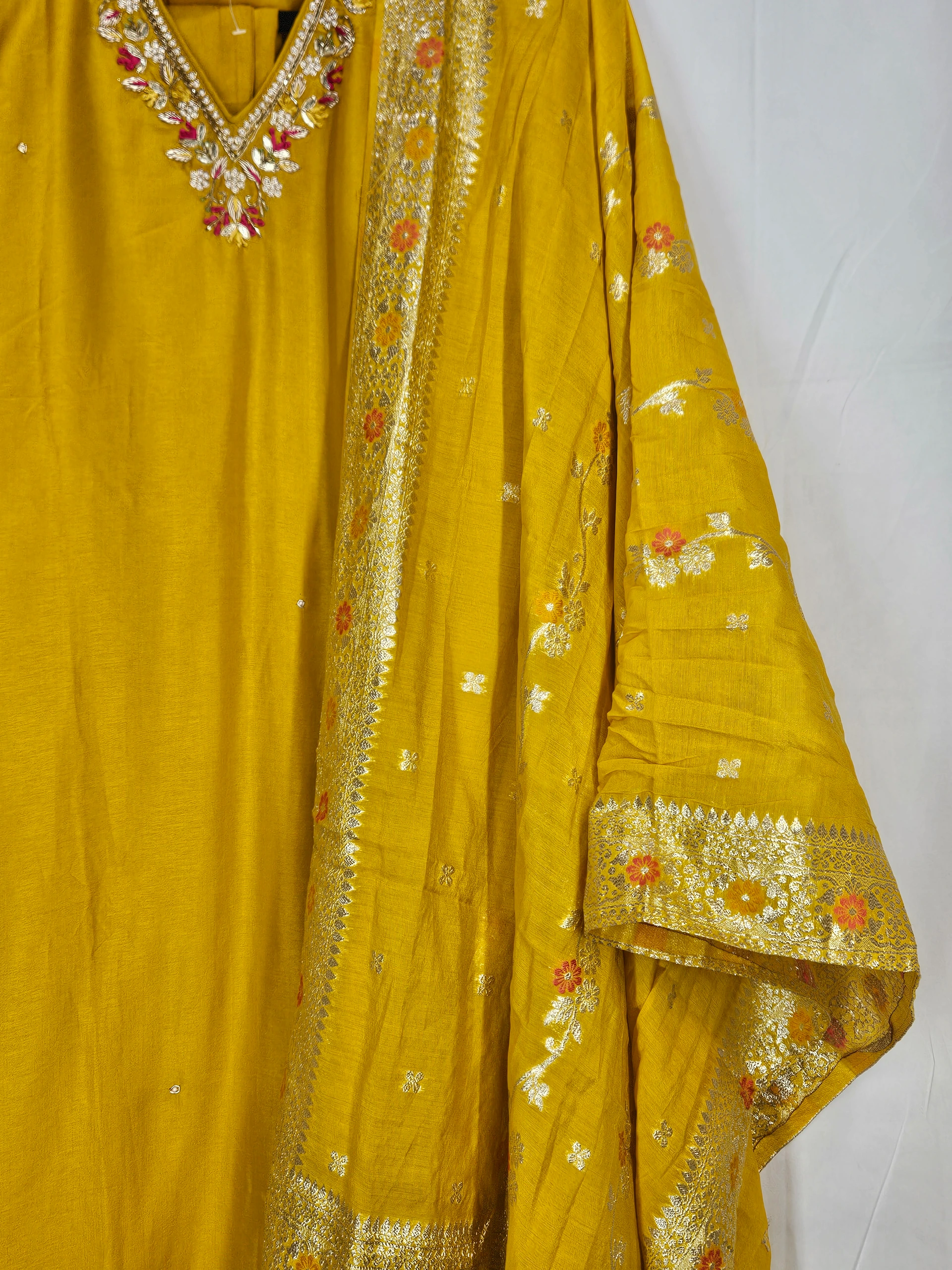 Yellow pure Dola silk dress with intricate golden embroidery, floral patterns, and embellished neckline, perfect for weddings and festive celebrations.