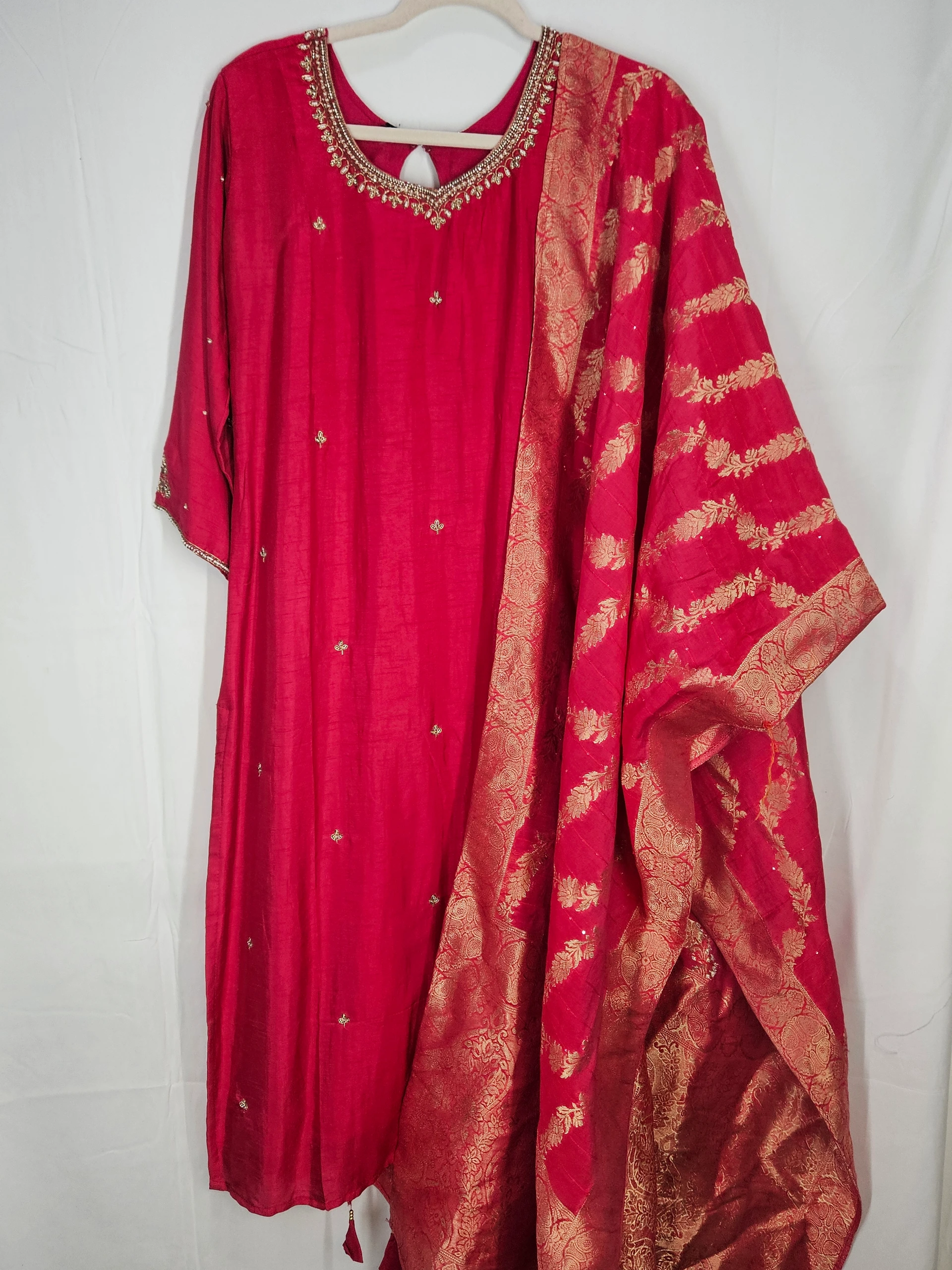 Pure Dola Silk ethnic dress in vibrant red with intricate golden embroidery, paired with a matching dupatta featuring gold zari patterns. Perfect for weddings and festive occasions.