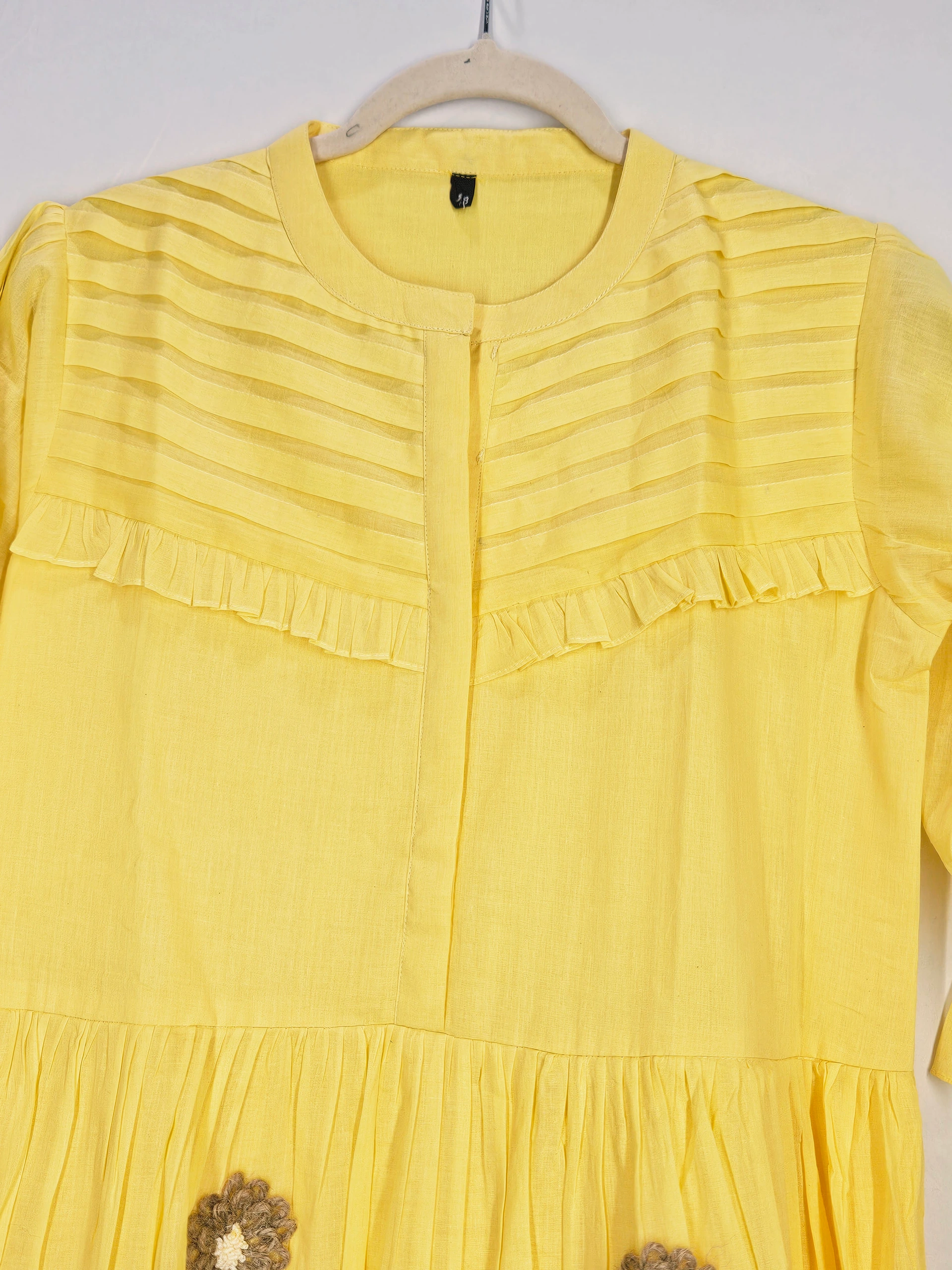 Yellow mul cotton ethnic dress with pleated yoke, ruffle details, and floral embroidery, perfect for festive occasions.