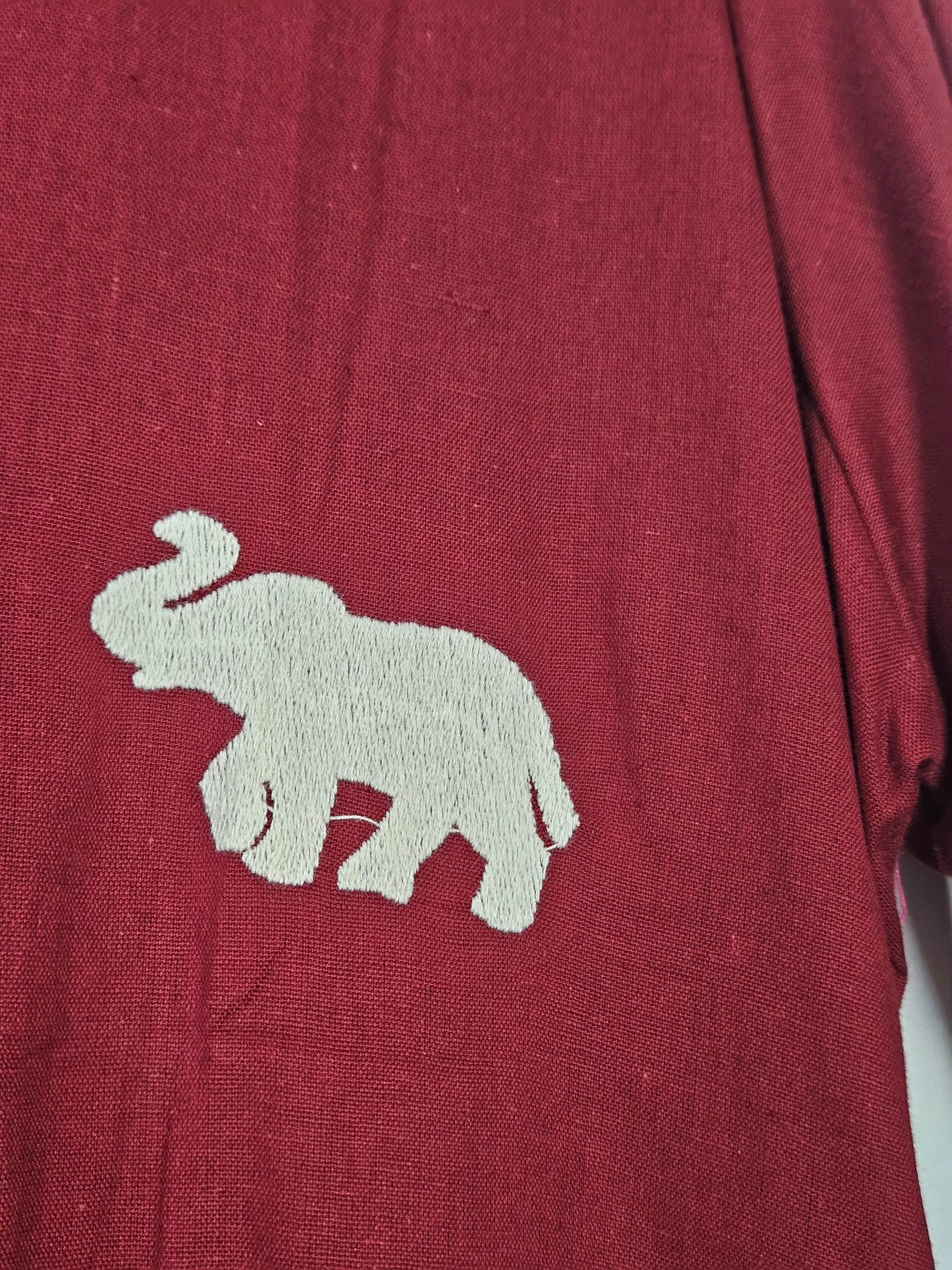 Pure mul cotton frock in deep maroon with an embroidered white elephant motif, showcasing breathable fabric and ethnic charm.
