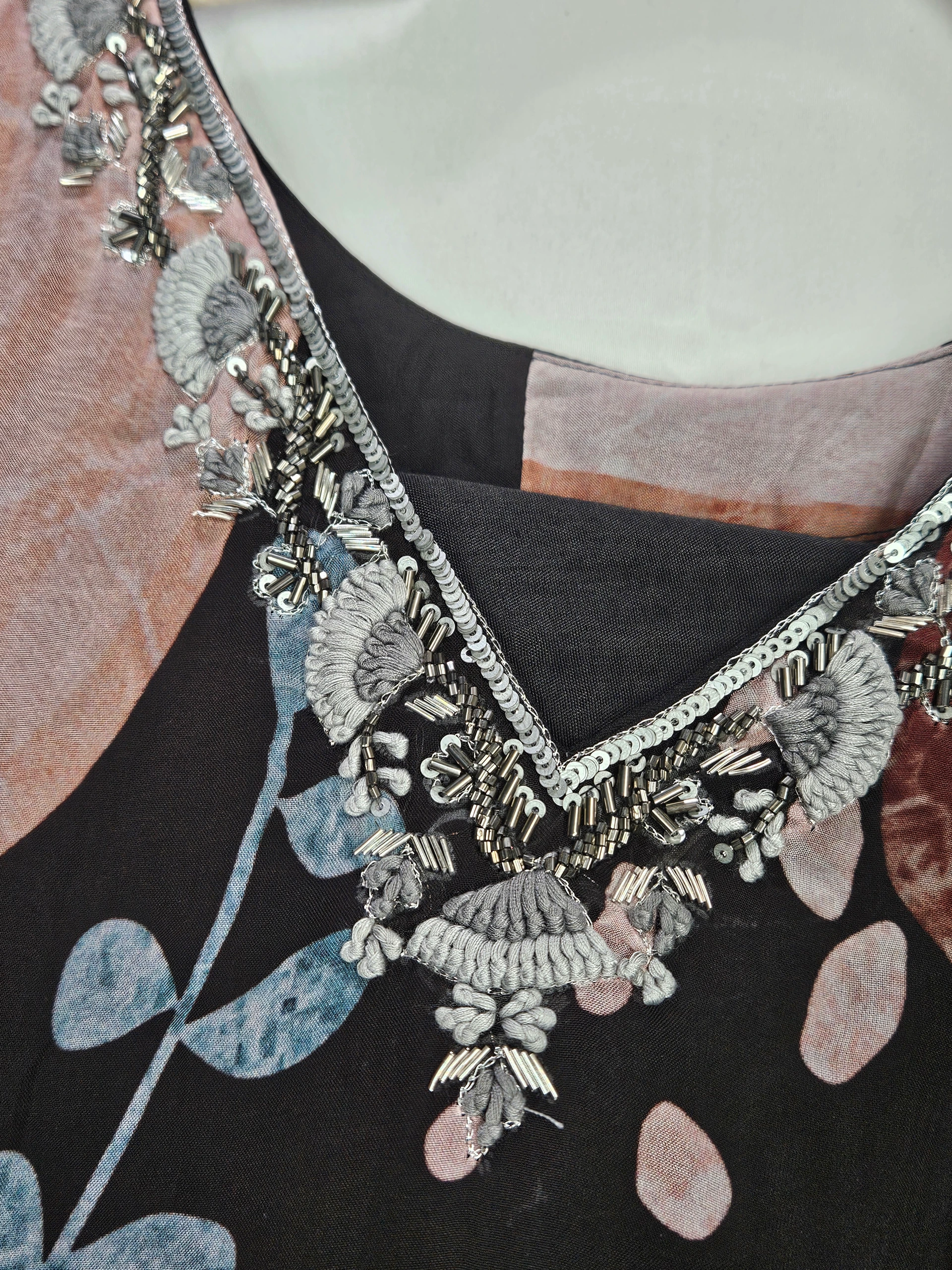 Pure georgette ethnic gown with intricate silver embroidery on the neckline, featuring floral and abstract patterns in soft pink, blue, and black tones.