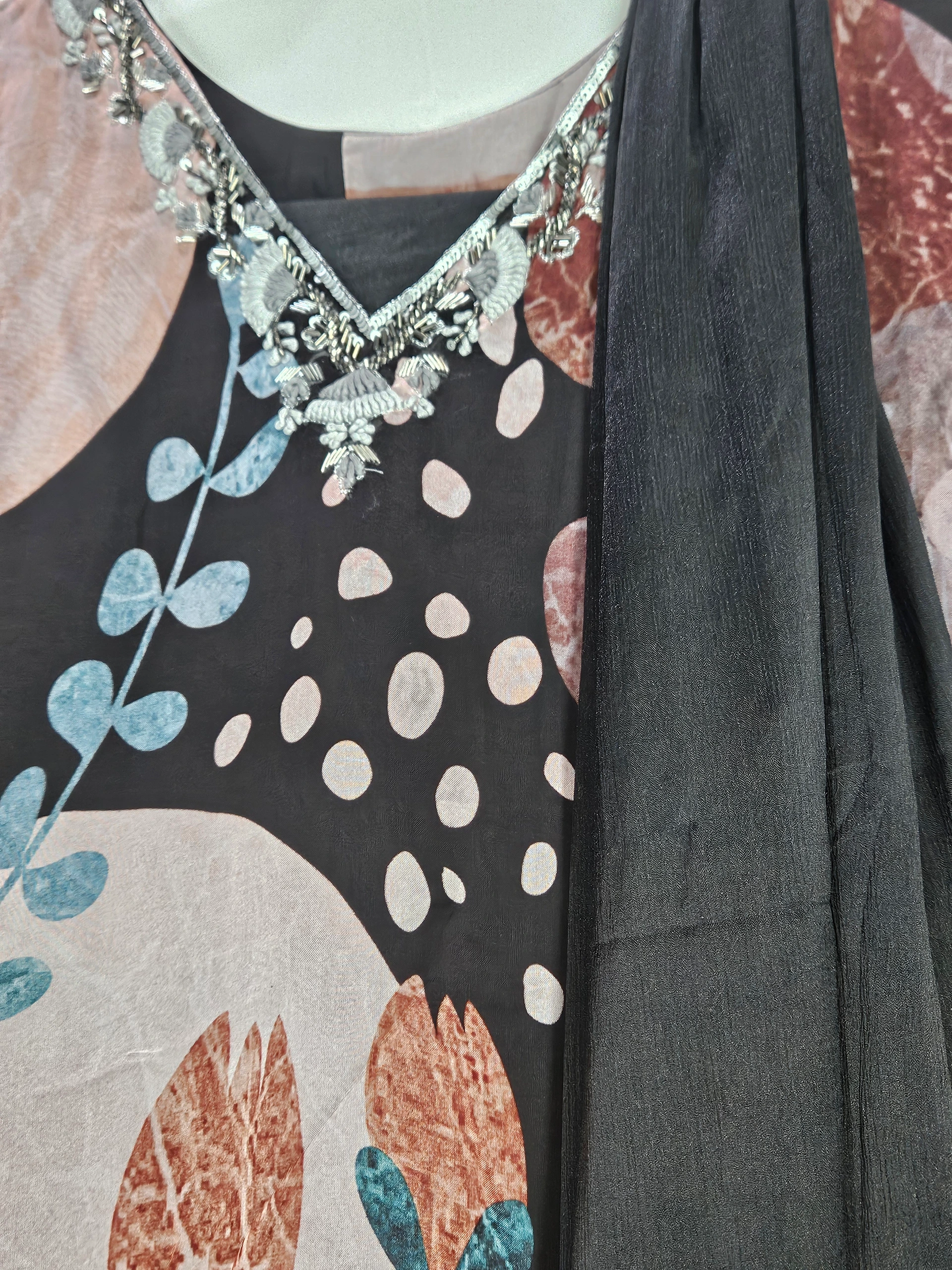 Pure georgette ethnic gown with floral and abstract prints in earthy tones, adorned with silver embroidery on the neckline, paired with a black dupatta.