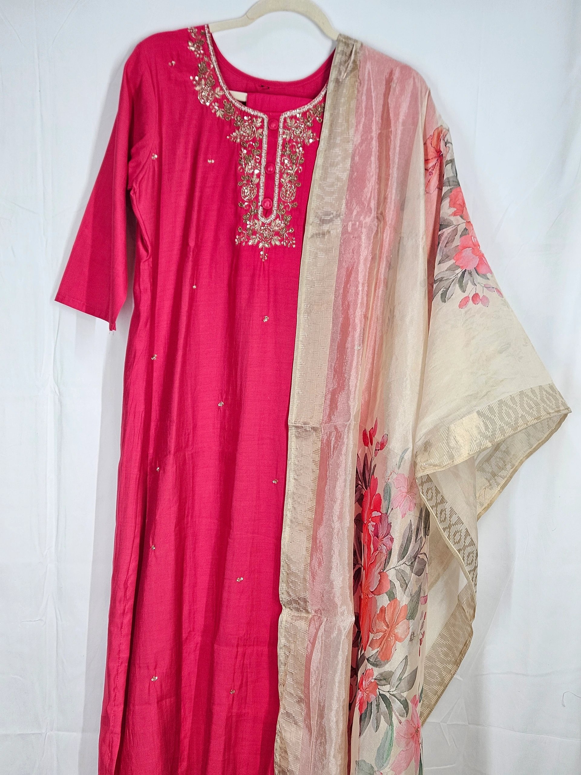 Pink pure muslin ethnic dress with intricate embroidery on the neckline, paired with a beige floral-patterned dupatta. Perfect for weddings and festivals.