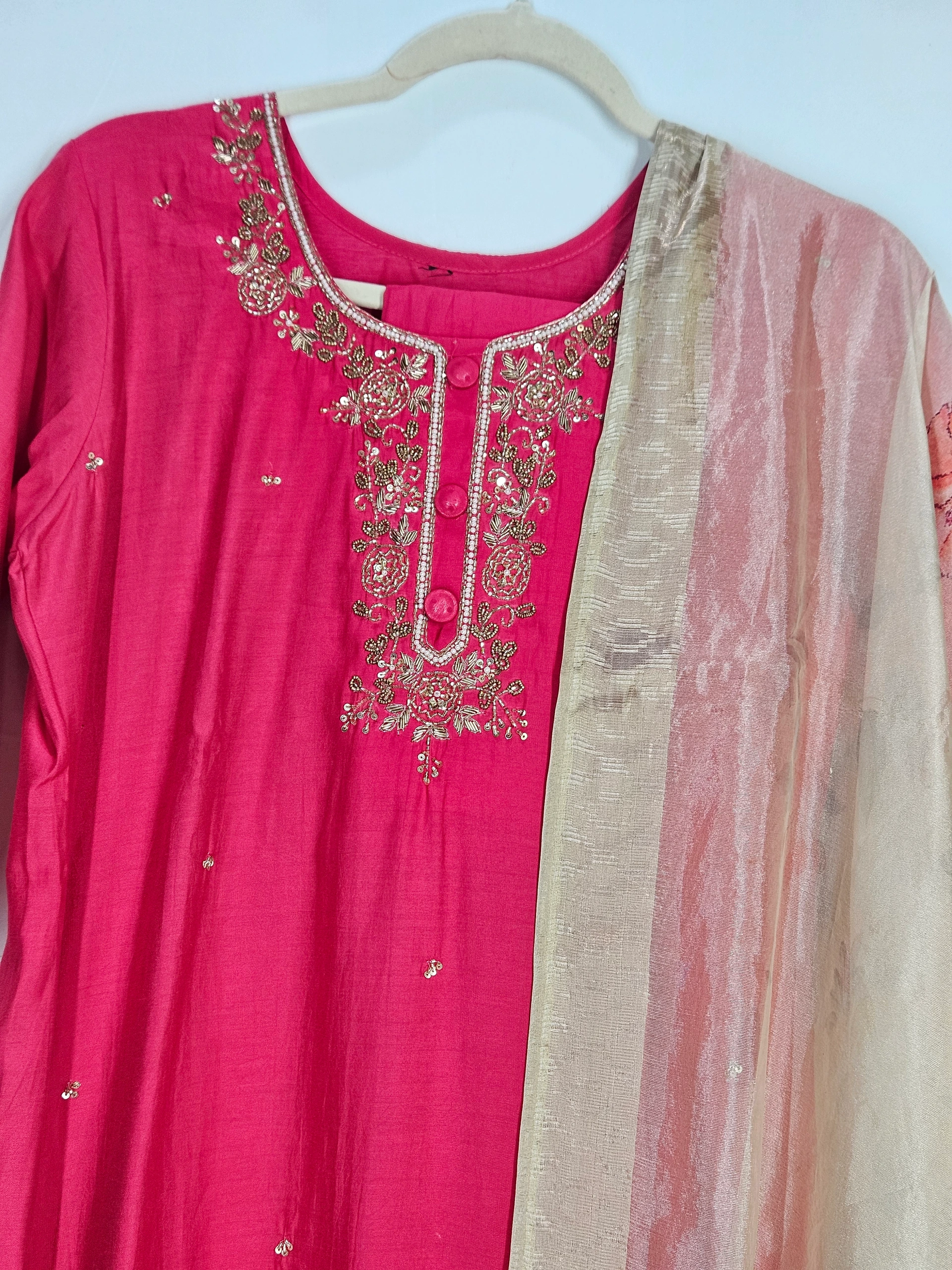 Pink pure muslin ethnic dress with intricate floral embroidery on the neckline, paired with a pastel beige dupatta featuring subtle shimmer accents.