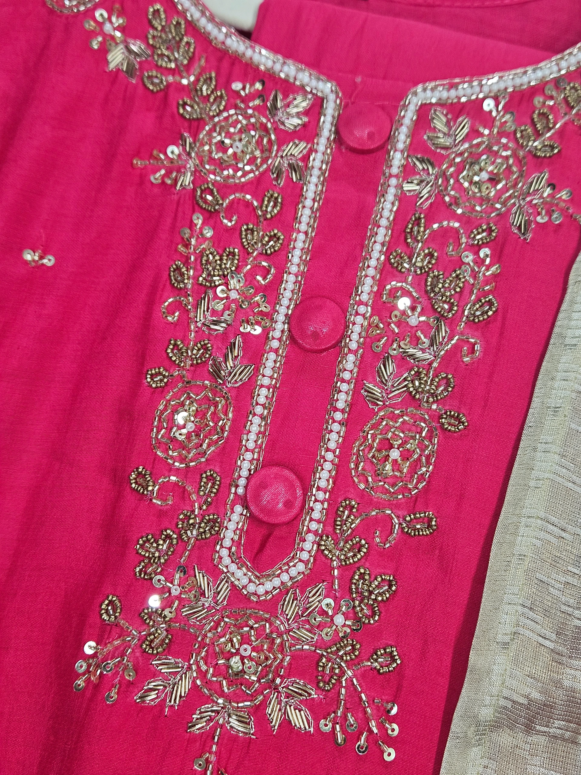 Pink pure muslin ethnic dress with intricate golden floral embroidery and sequin detailing, perfect for weddings and festivals.