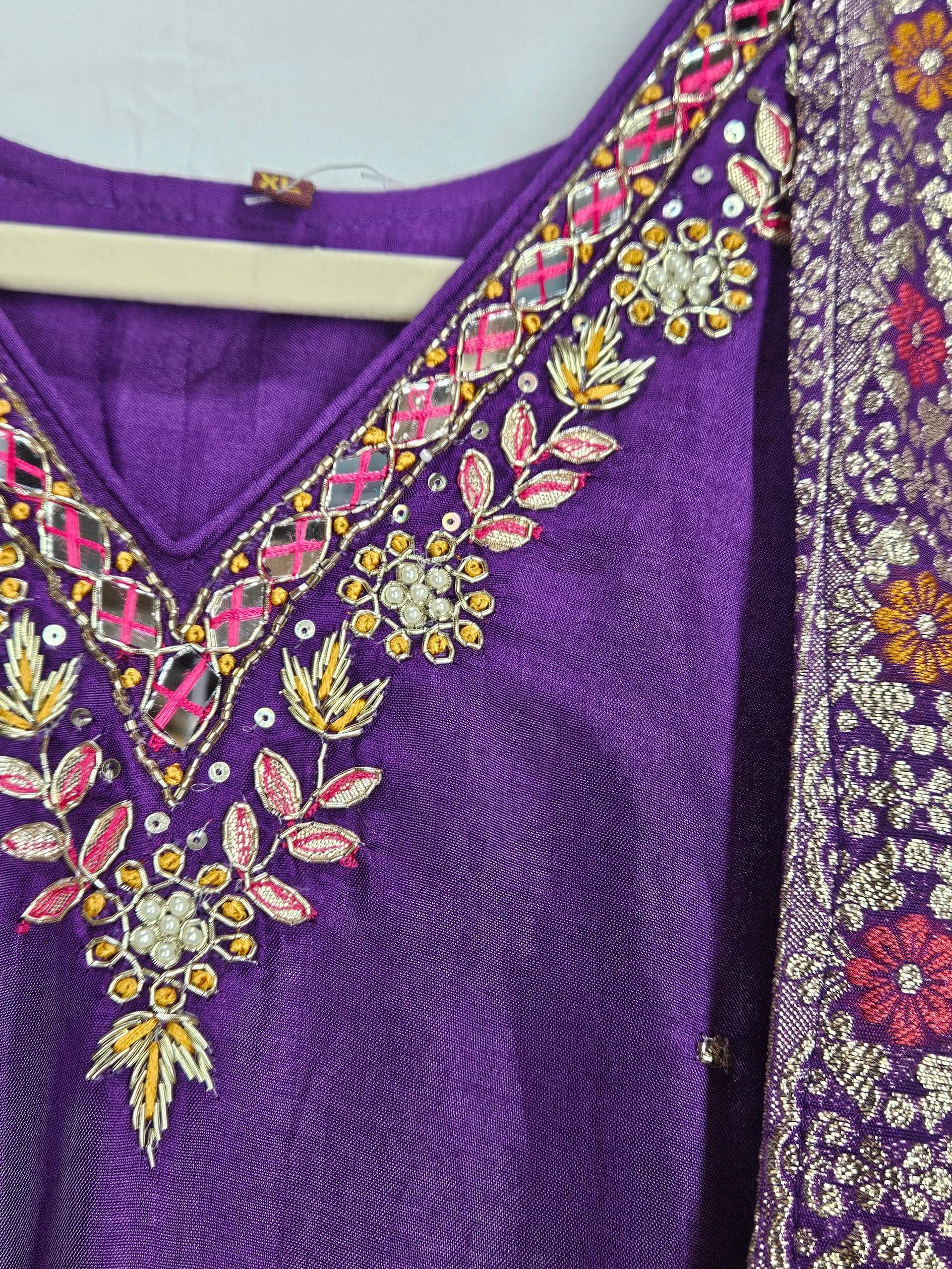 Purple Pure Dola Silk dress with intricate floral embroidery in gold, pink, and white, featuring a V-neckline and rich ethnic detailing.
