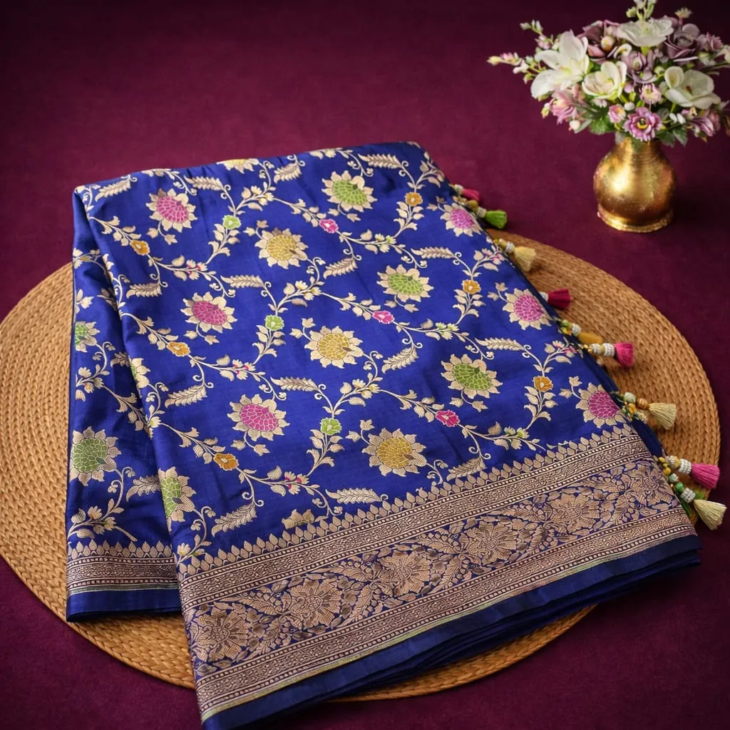 Luxurious blue Banarasi Katan silk saree featuring intricate multicolor meenakari floral weaving, displayed elegantly.